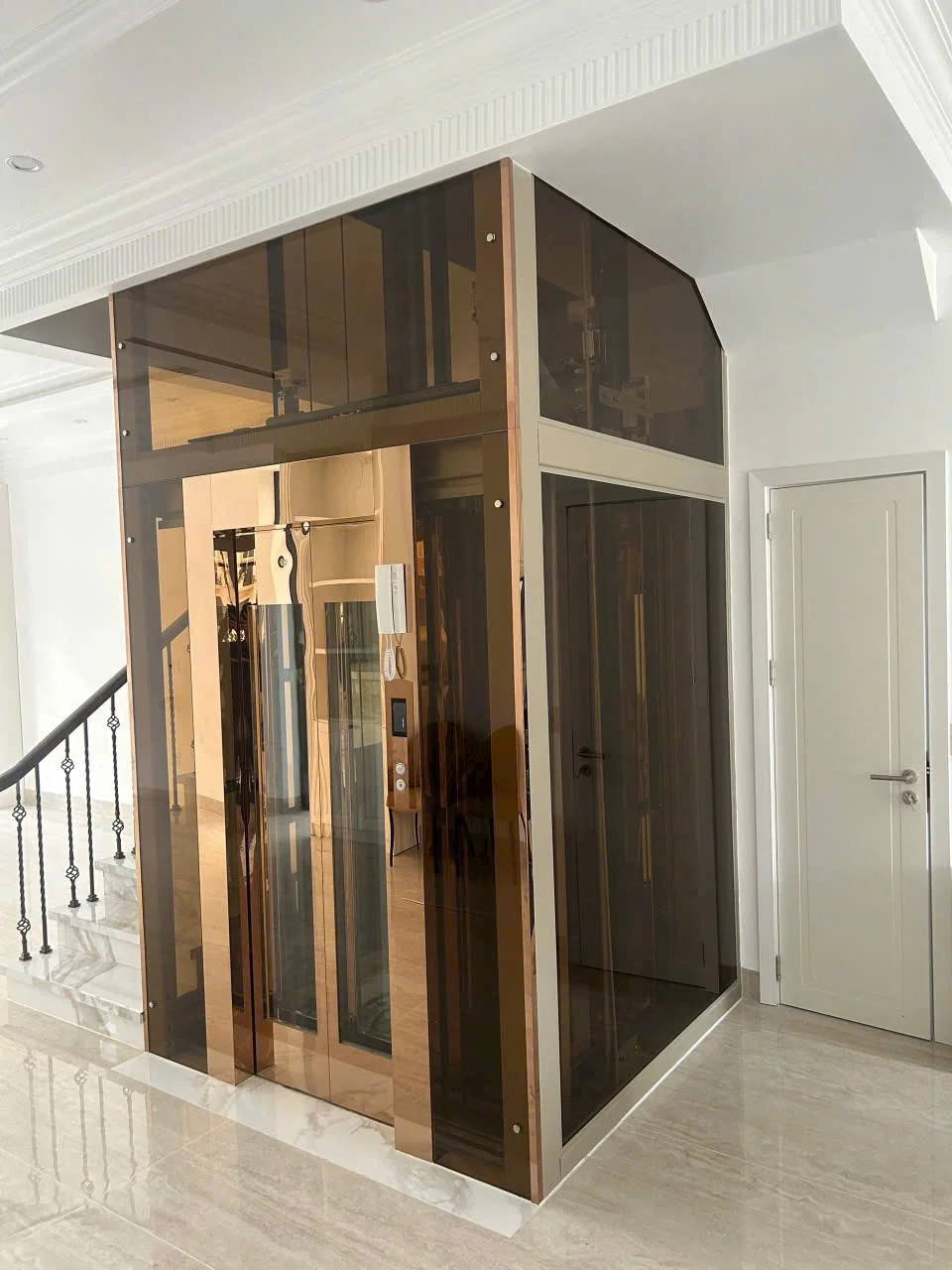 Thang kính tông nâu và kim loại màu ấm bên cầu thang trong nhà